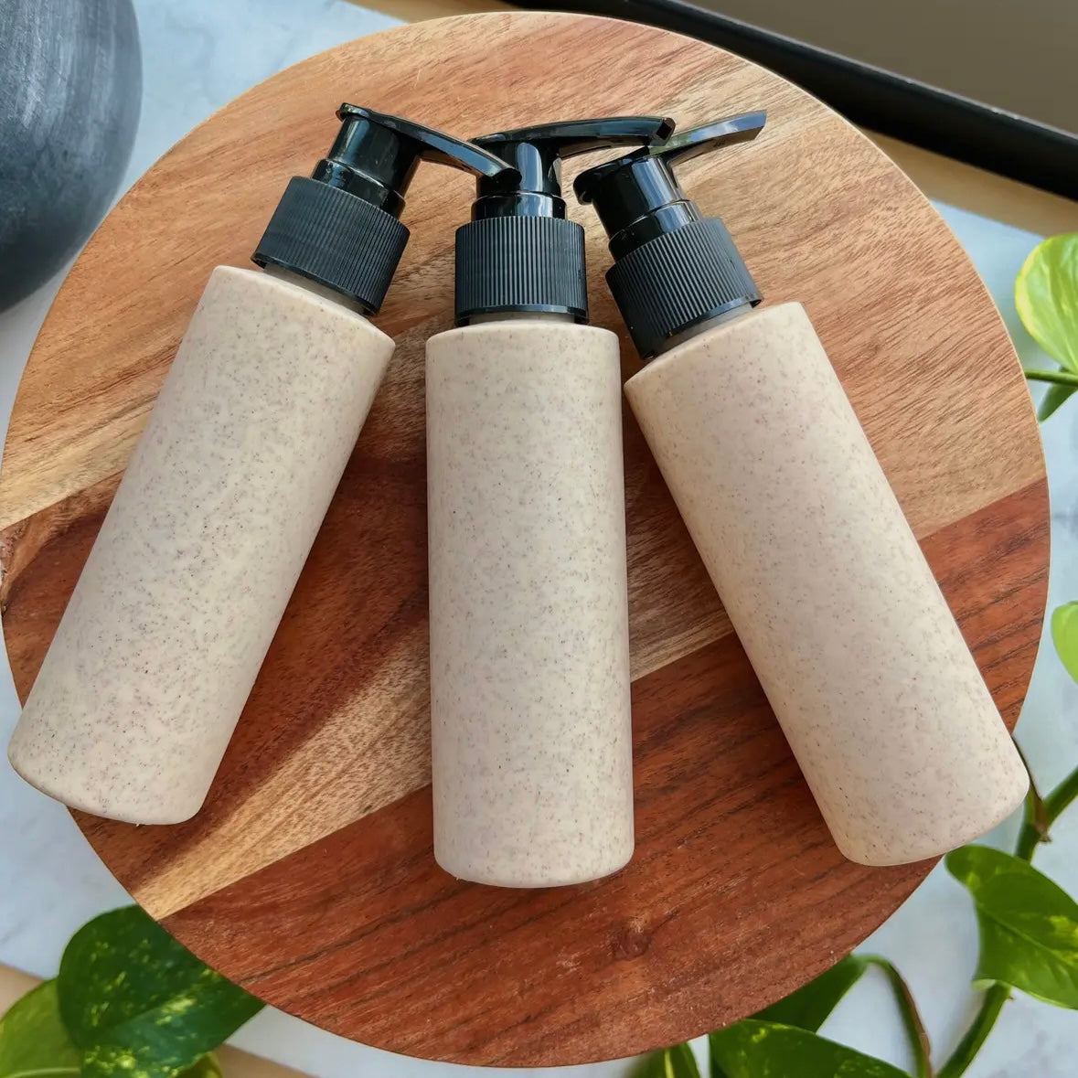Three beige bottles with black pumps on a wooden surface