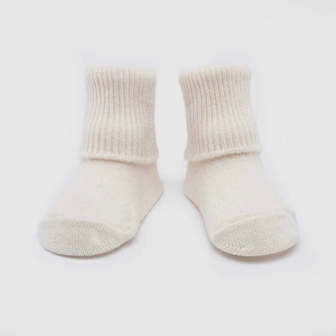 Pair of cream colored socks on a white background