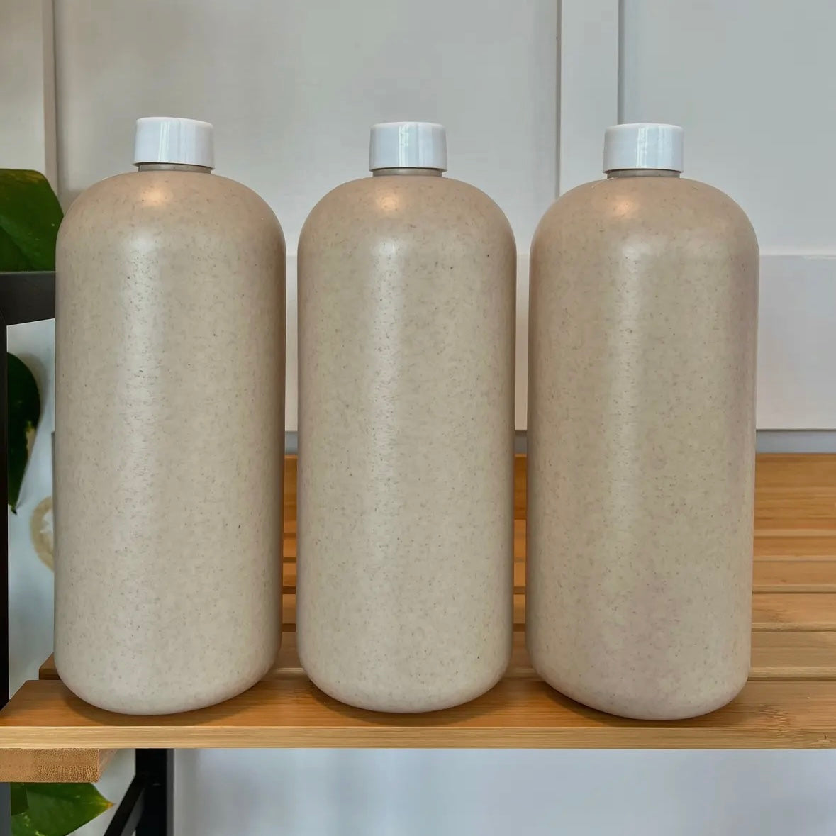 Three beige bottles with white caps on a wooden surface.