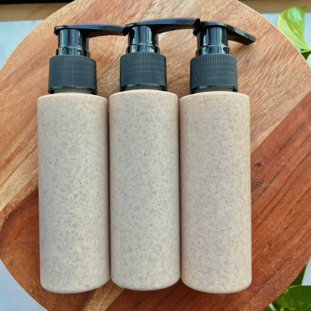Three beige bottles with black pumps on a wooden surface