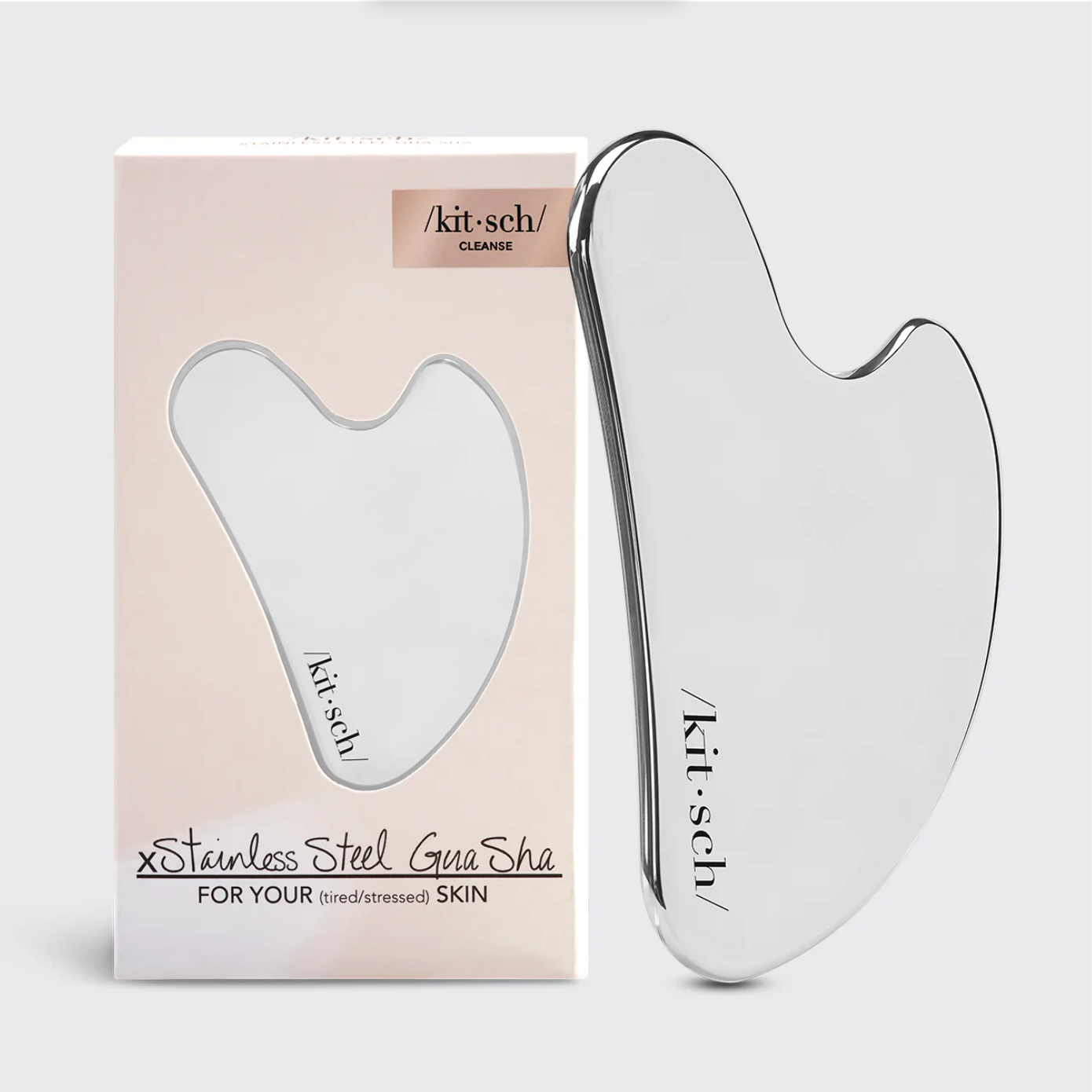 Silver Gua Sha tool with 'kit-sch' branding next to its packaging on a light gray background